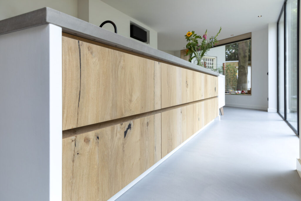 keuken laten maken, keuken bouwer, op maat keukens, op maat gemaakte keukens, luxe keukens, vogels keukens Helmond, Nuenen, Waalre, Stiphout, Liessel, Helmond, Eindhoven, Bladel, Pijnacker, Rotterdam Vlakinbouw inductiekookplaat - Keuken in Regio Rotterdam, Koperkleurige spoelbakRonde deuren hoge kast, Composiet werkblad, Recirculatie schuine afzuigkap, Ronde vormen bij keuken, Keukenblad van Balsabeton "Robuste", Apparatenwand met rustiek eiken fineer, Wandmeubel passend bij keuken, Keukeneiland met Balsabeton werkblad, Industriële keuken met betonnen blad, Quooker reservoir weggewerkt achter ladefrontenDoorlopende houtnerf in fronten