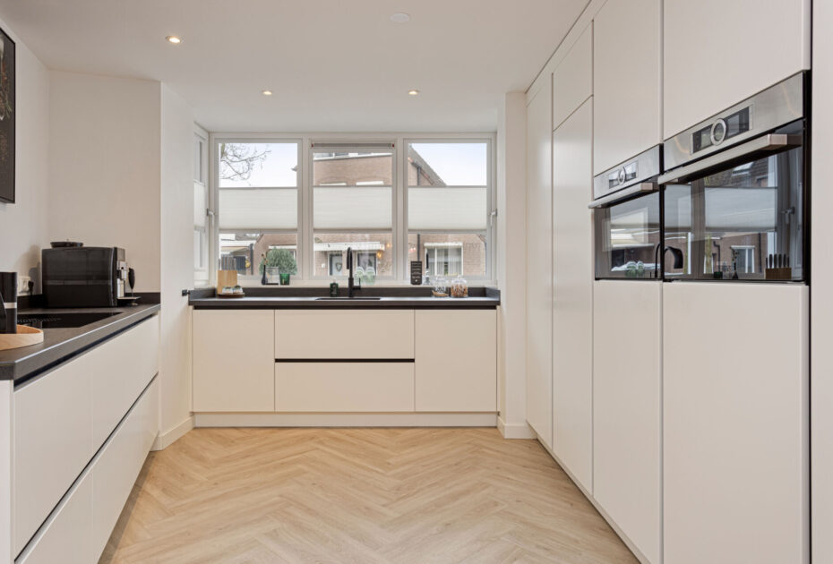 Moderne keuken Helmond, Keuken Brouwhuis, Witte moderne keuken, zwarte greeplijsten, zijdeglans lak fronten, zwarte grepen, witte keuken Helmond, moderne keuken, keuken met modern design, hoogwaardig keukenontwerp, stijlvolle keuken, luxe keuken, keukeninterieur, horizontale greeplijsten, horizontale zwarte greeplijsten, vlakinbouw kookplaat, kookplaat met afzuiging, kookplaat met geïntegreerde kookplaat, geïntegreerde kookplaat, inductiekookplaat met afzuiging, keramisch werkblad, keramische werkblad met veegplinten, Quooker kraan Flex, Franke Fragranite zwart, zwarte quooker. Zwarte verticale greeplijsten, verticale greeplijsten, kastenwand, apparatenwand, moderne keuken met apparatenwand, kastenwand met ovens.