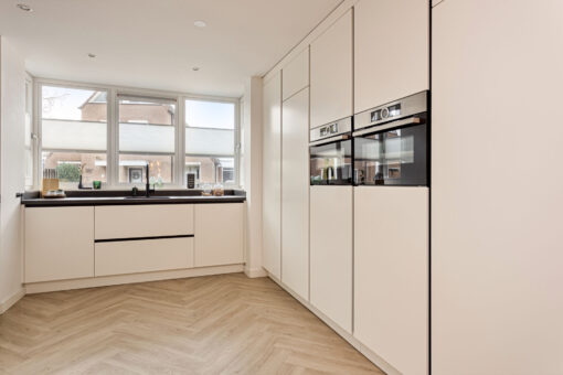 Moderne keuken Helmond, Keuken Brouwhuis, Witte moderne keuken, zwarte greeplijsten, zijdeglans lak fronten, zwarte grepen, witte keuken Helmond, moderne keuken, keuken met modern design, hoogwaardig keukenontwerp, stijlvolle keuken, luxe keuken, keukeninterieur, horizontale greeplijsten, horizontale zwarte greeplijsten, vlakinbouw kookplaat, kookplaat met afzuiging, kookplaat met geïntegreerde kookplaat, geïntegreerde kookplaat, inductiekookplaat met afzuiging, keramisch werkblad, keramische werkblad met veegplinten, Quooker kraan Flex, Franke Fragranite zwart, zwarte quooker. Zwarte verticale greeplijsten, verticale greeplijsten, kastenwand, apparatenwand, moderne keuken met apparatenwand, kastenwand met ovens.