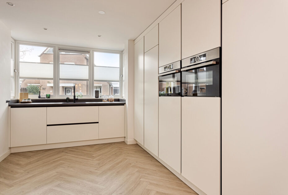 Moderne keuken Helmond, Keuken Brouwhuis, Witte moderne keuken, zwarte greeplijsten, zijdeglans lak fronten, zwarte grepen, witte keuken Helmond, moderne keuken, keuken met modern design, hoogwaardig keukenontwerp, stijlvolle keuken, luxe keuken, keukeninterieur, horizontale greeplijsten, horizontale zwarte greeplijsten, vlakinbouw kookplaat, kookplaat met afzuiging, kookplaat met geïntegreerde kookplaat, geïntegreerde kookplaat, inductiekookplaat met afzuiging, keramisch werkblad, keramische werkblad met veegplinten, Quooker kraan Flex, Franke Fragranite zwart, zwarte quooker. Zwarte verticale greeplijsten, verticale greeplijsten, kastenwand, apparatenwand, moderne keuken met apparatenwand, kastenwand met ovens.