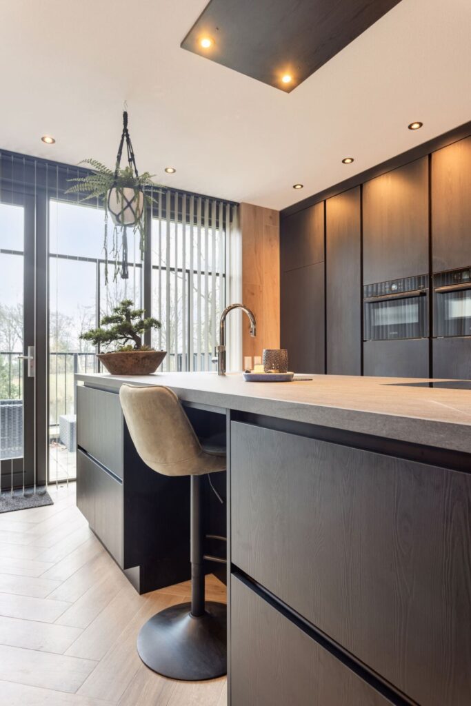 Moderne keuken Someren, keukenstudio Someren, keuken op maat someren, Keramisch werkblad, Kookeiland, kastenwand, , Geïntegreerde Bora kookplaat met afzuiging, Franke Fragranite witte vlakinbouw spoelbak, Quooker kraan Flex chroom, Zwart houtdecor fronten, Zwarte horizontale en verticale greeplijsten.