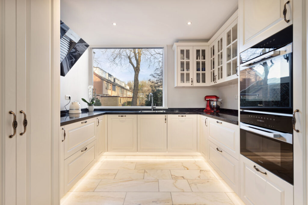 Klassieke keuken Delft, keukenstudio Delft, keuken op maat Delft, Klassieke keuken Rotterdam, keukenstudio Rotterdam, keuken op maat Rotterdam, composiet werkblad, Geïntegreerde kookplaat, rvs vlakinbouw spoelbak, Gelakte fronten, klassieke fronten, keuken met greep.