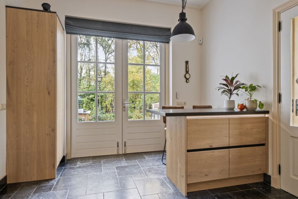 Eiken keukeneiland bij terrasdeuren met hanglamp en decoratieve planten