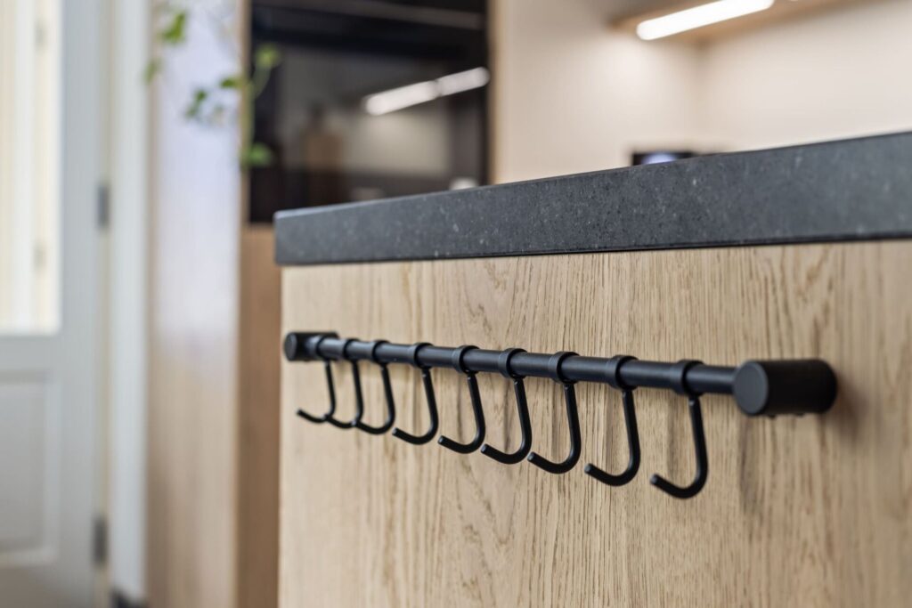 Detail van zwart hangrek met haken aan eiken keukeneiland