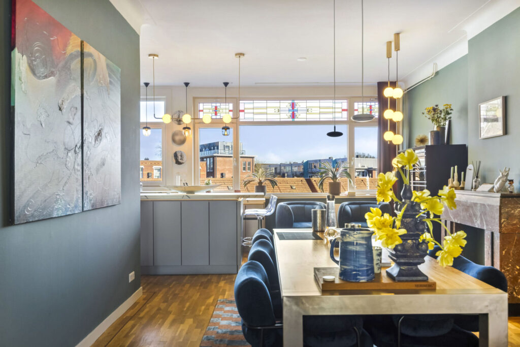 Eethoek met houten tafel, fluwelen stoelen en hanglampen bij glas-in-lood ramen