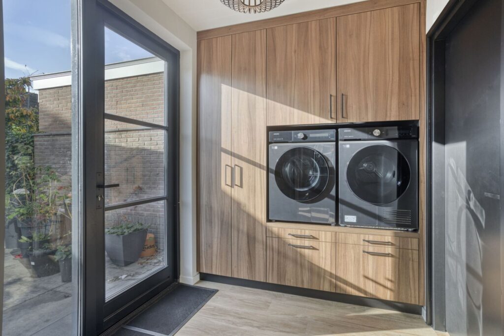 Bijkeuken op maat met ingebouwde wasmachine en droger in houten kastenwand