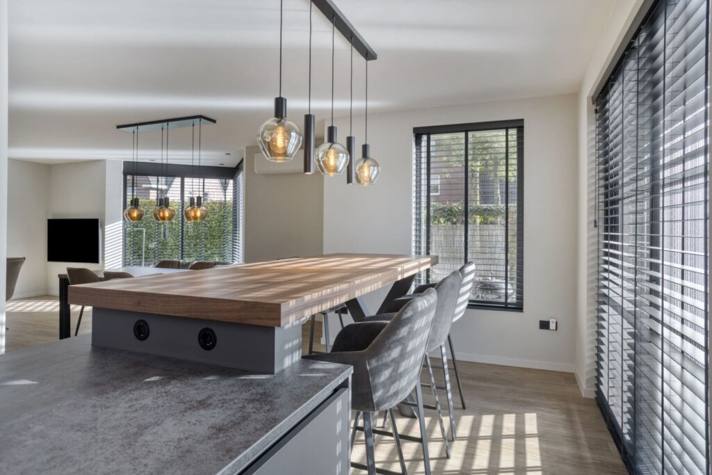 Houten bartafel met hanglampen en zicht op woonkamer met grote raampartij