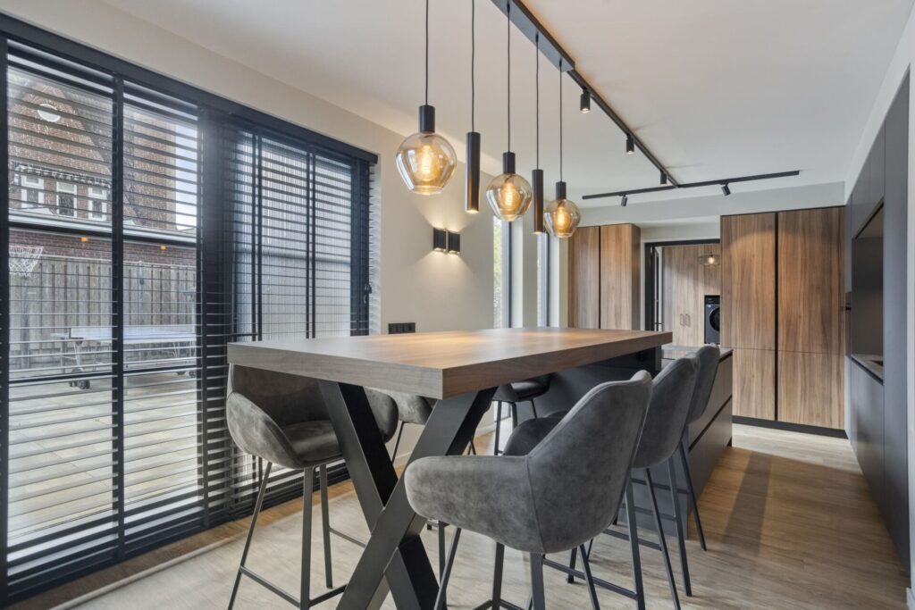 Hoge bartafel met grijze fluwelen barkrukken en hanglampen voor houten kastenwand