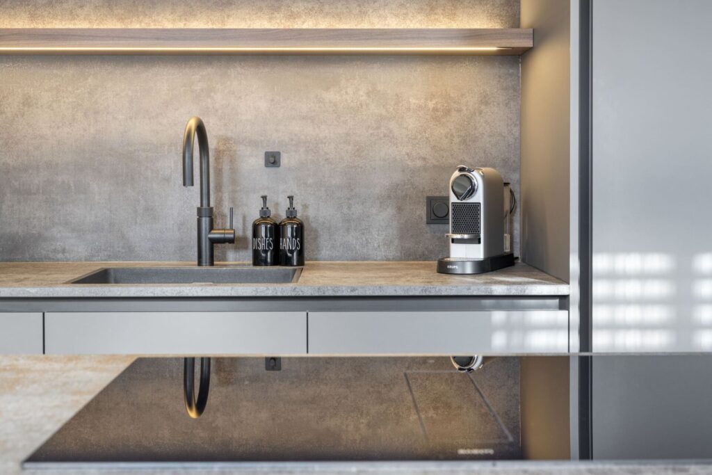 Zwarte keukenkraan met wasbak, zeeppompjes en Nespresso koffiemachine in moderne keuken